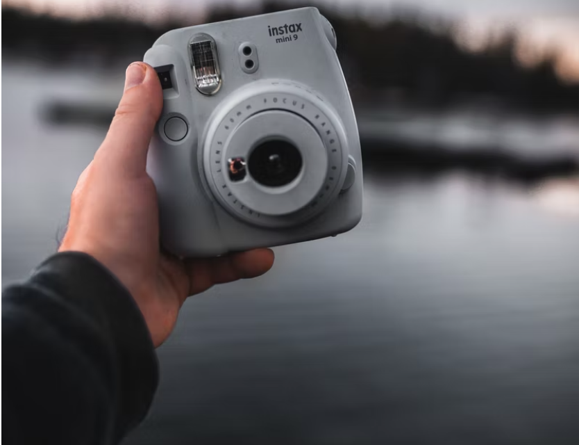 Hand holding camera with lake in the background