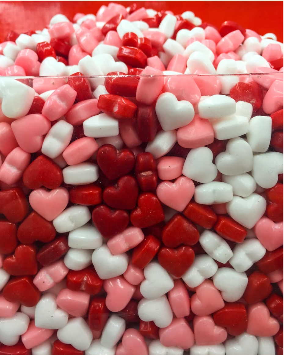 Clear jar of many candy hearts, red, pink and white.