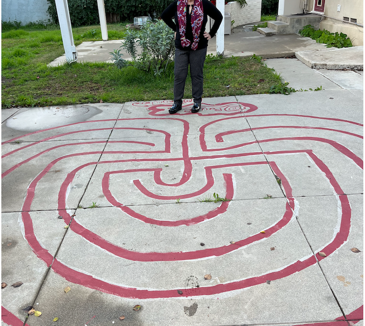 woman standing at the edge of a small outdoor labyrinth.