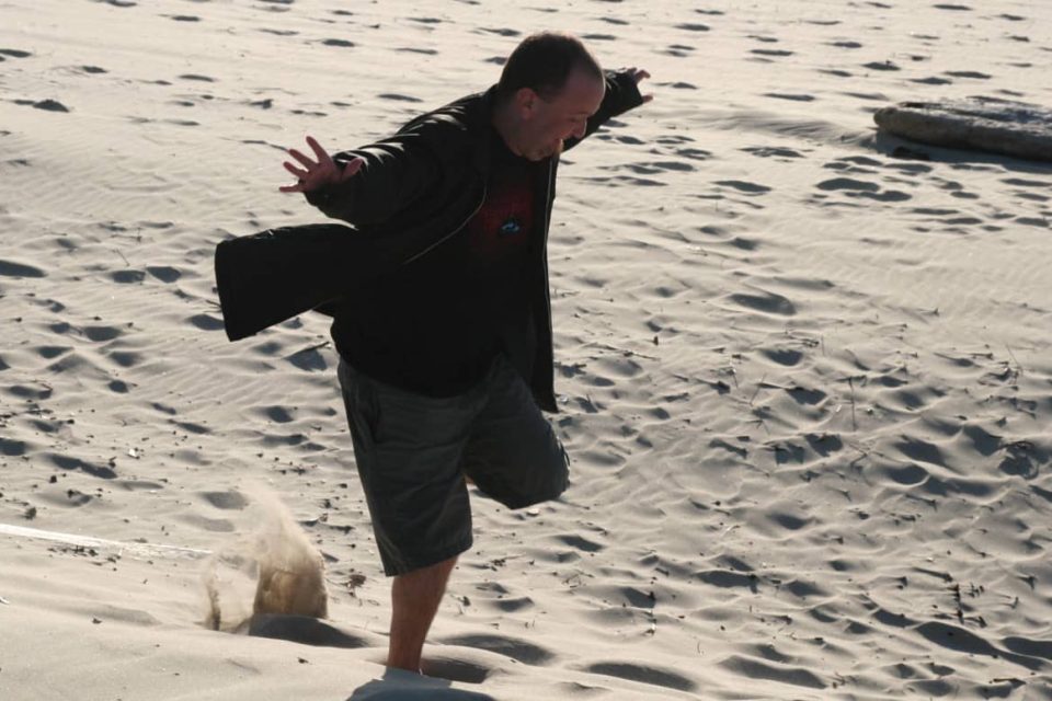 An image of a happy guy running through sand on the beach