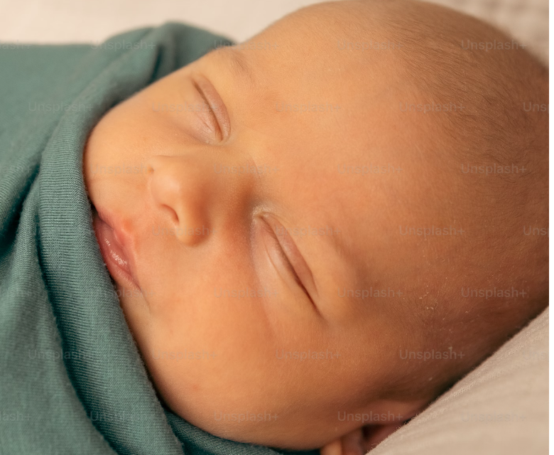 newborn infant swaddled in green blanket