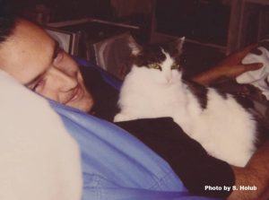 a man lying in a blue bean bag with a black and white cat on his lap