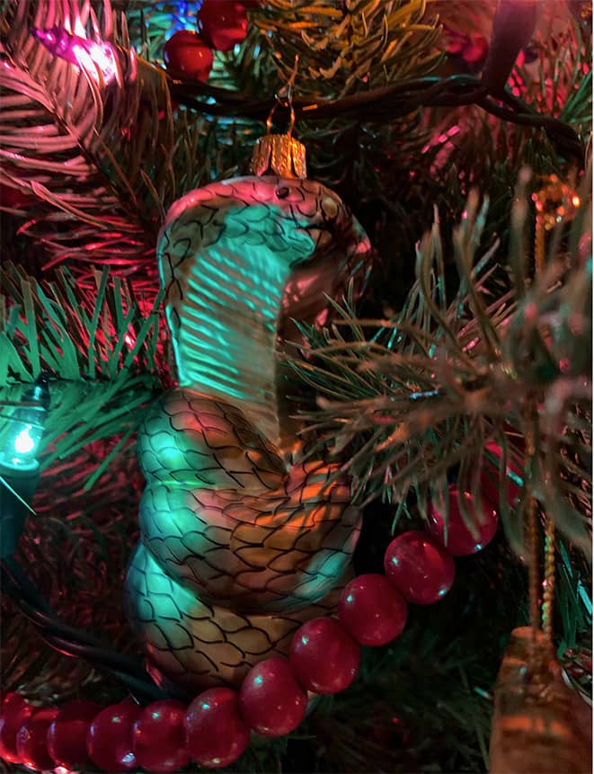 A close up photo of a glass cobra ornament hanging on a Christmas tree