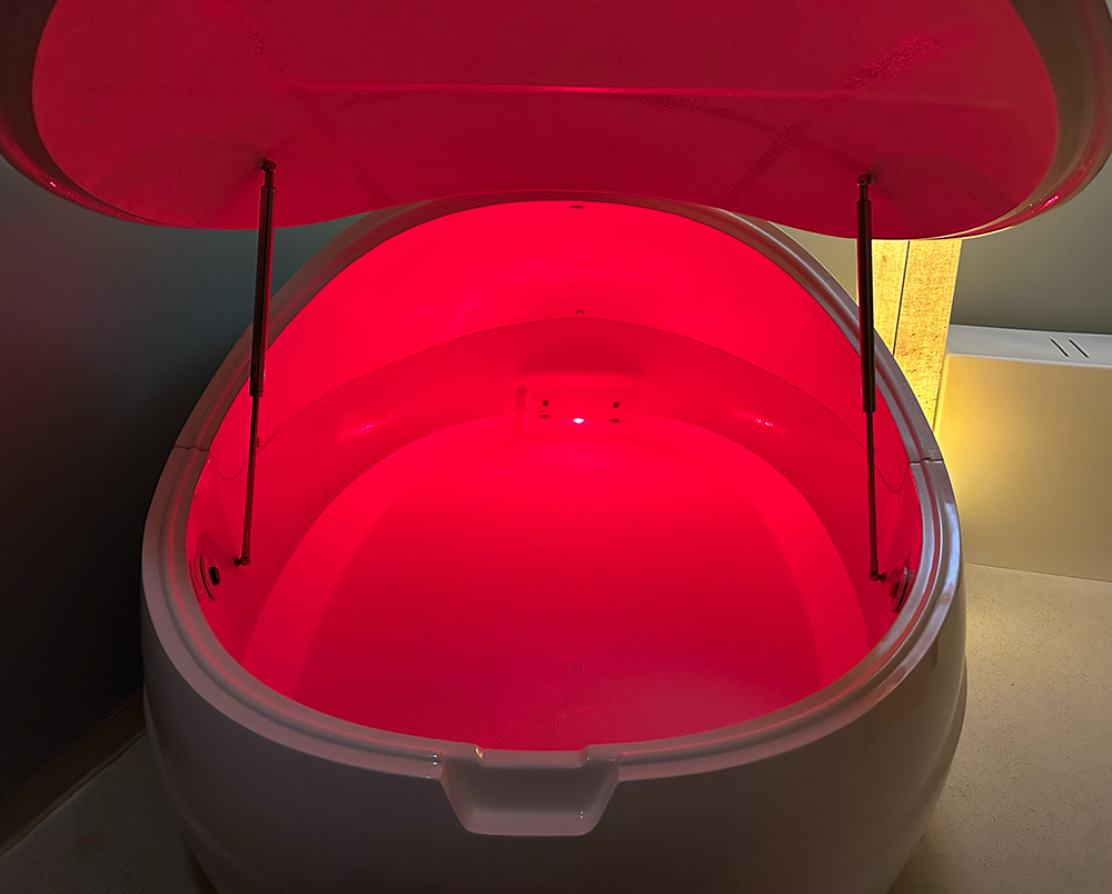 A photo of an open isolation float tank with red L.E.D. light