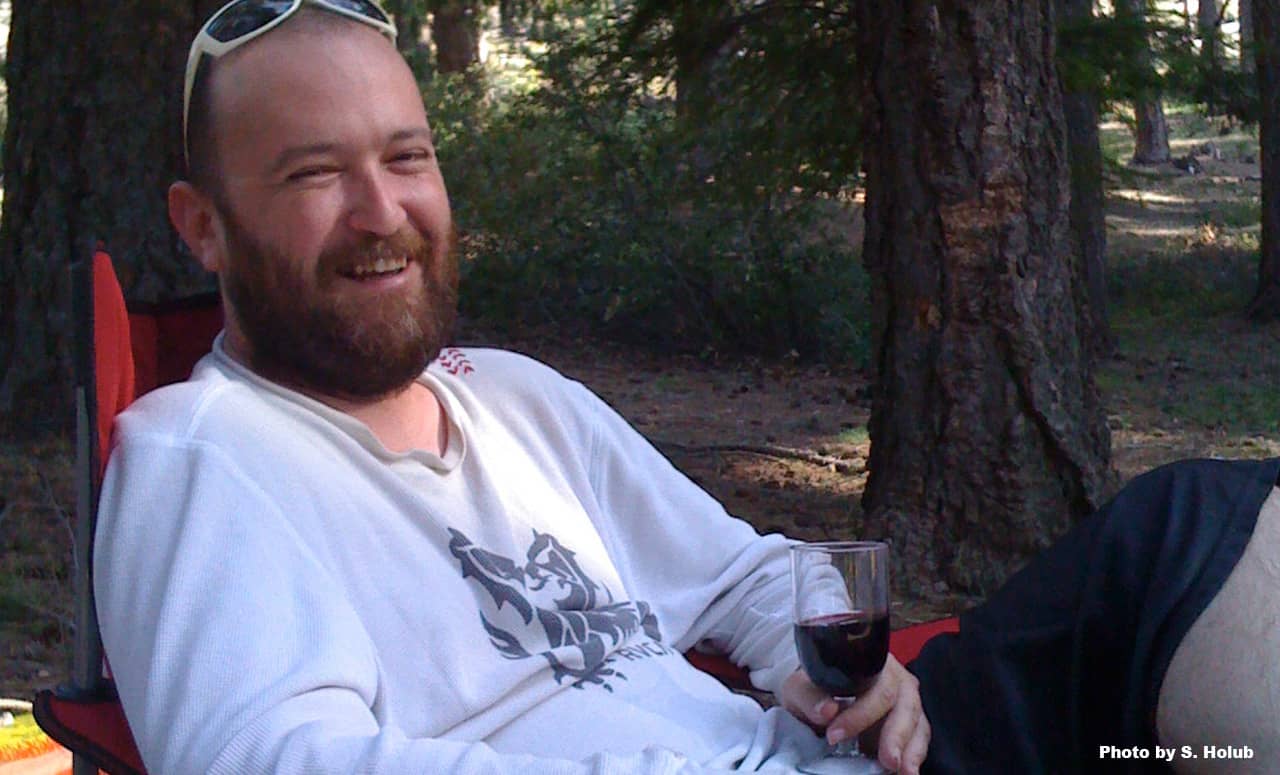 A happy guy with a wine glass sitting outside
