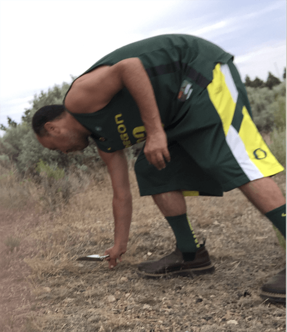 photo of a person bending down to pick up a rock