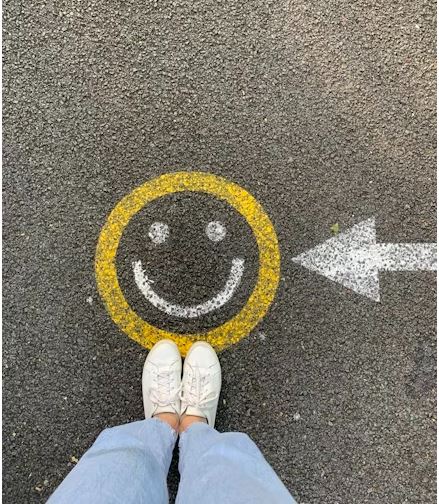 Person with feet on a happy face on the street.