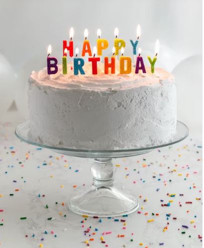 A cake with lit candles that says Happy Birthday.