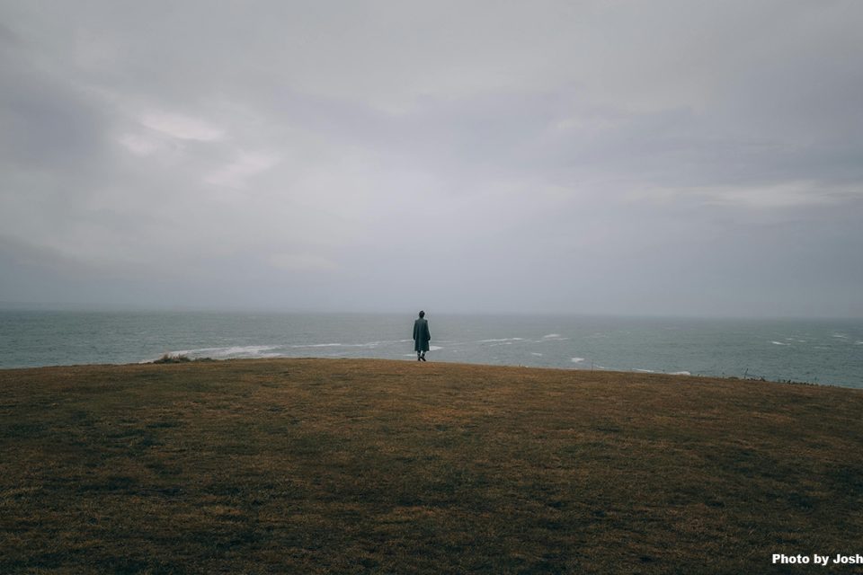 a lone person seen from a distance against the backdrop of the ocean