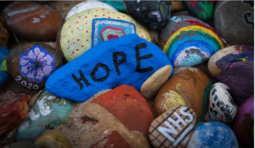 A pile of painted rocks with a blue one that says Hope.