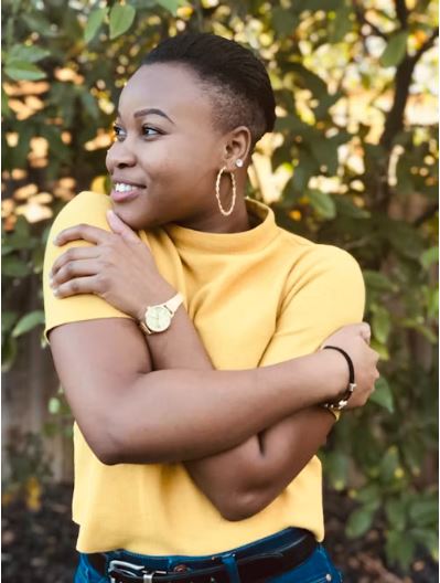 Black woman smiling and hugging herself.