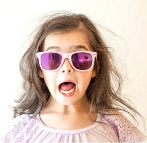 Surprised face of little girl wearing colored sun glasses.