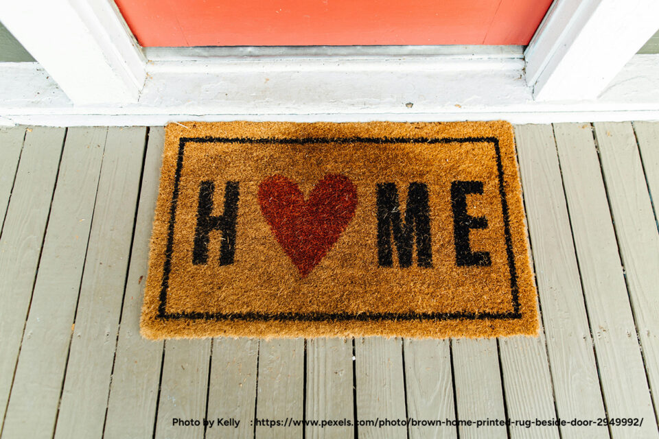 a photo of a mat in front of a front door with the word home where the o is a heart