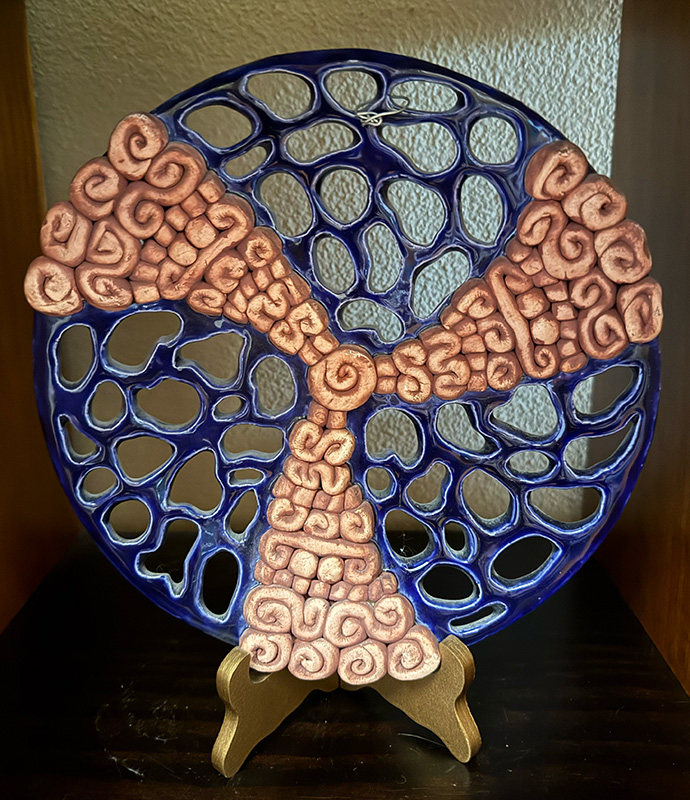 A funky blue ceramic plate shape with holes and spirals