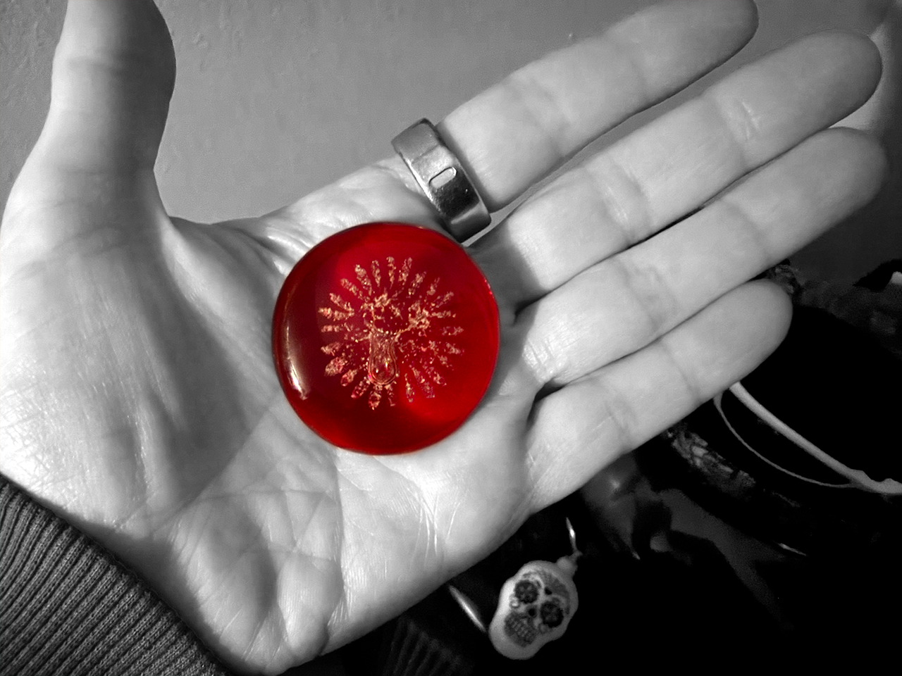 a hand holding a red "Bobrock" artisan glass keepsake with ashes