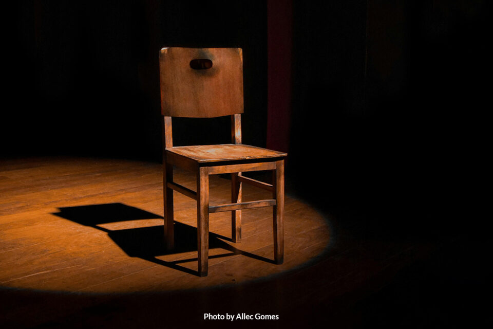 empty wooden chair in a dark room with a spotlight